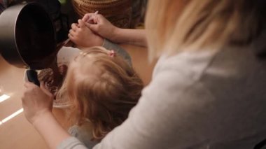 Küçük bir kız annesinin çikolata pişirmesine yardım eder.