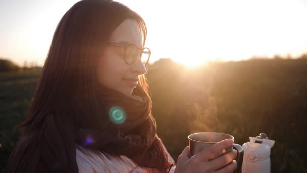 Une jeune femme verse le thé chaud d'un thermos au coucher du soleil — Video