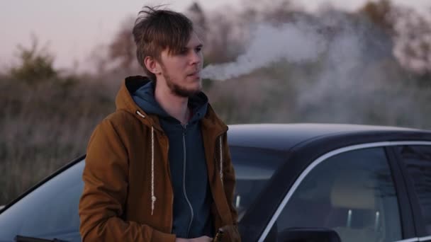 Ritratto di un giovane sulla strada Fumare sigarette elettroniche in macchina — Video Stock