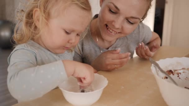 Мать и маленькая дочь разговаривают за кухонным столом во время приготовления пищи — стоковое видео