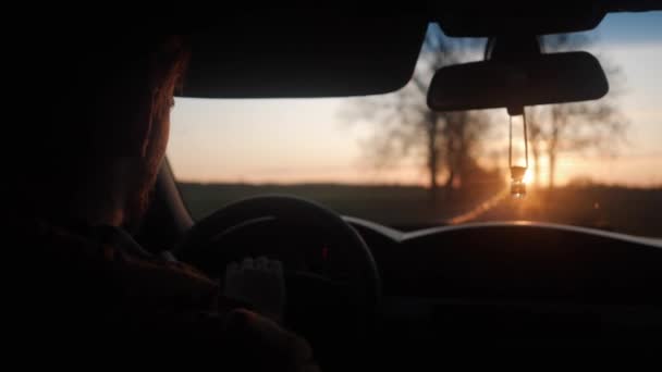 Ein junger Mann setzt sich bei Sonnenuntergang hinters Steuer — Stockvideo