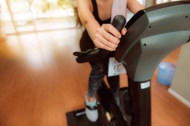 Spor, spor ve sağlıklı kavramı Bisiklete binme makine tanıtıcısı tutan kadın el.