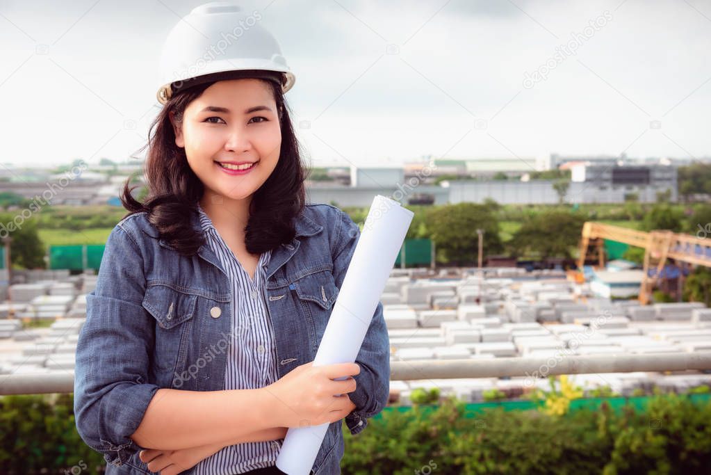 Portrait of engineer woman is holding paperwork at construction site background.