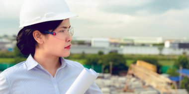 Mühendis kadın portresi inşaat site arka plan evrak tutuyor.