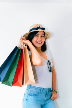 Kadın beyaz t-shirt giyiyor ve jean birçok alışveriş torbaları sürpriz duygu ile parlak beyaz arka plan önünde tutuyor