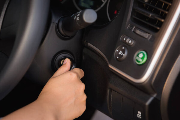 Close up of woman hand inserting a key to starting car engine.