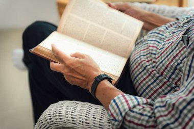 Üst düzey portre yakın adam oturma odasında bir kitap okuma.