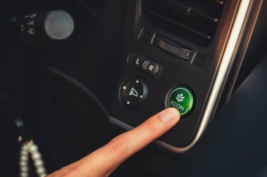 Kadın parmak portre yakından Eko modu açma/kapama düğmesi arabada Eko kavramı baskı yapıyor