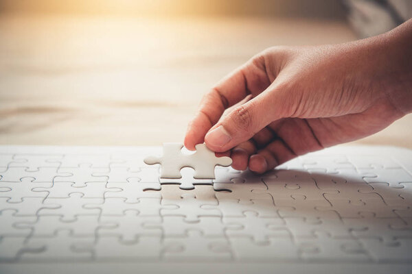 Closeup of woman hands fulfill the last piece of jigsaw puzzle to complete.,Business solutions, success mission concept.