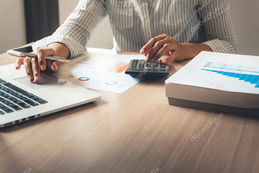 Close up portrait of businesswoman accountant using calculator and laptop for matching financial data saving in office room., Business financial, tax, accounting concept.