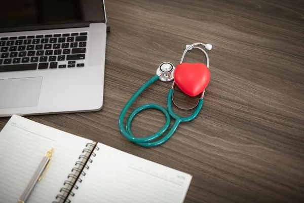 Health checkup concept, Doctor's desktop workspace with stethoscope and red heart model.