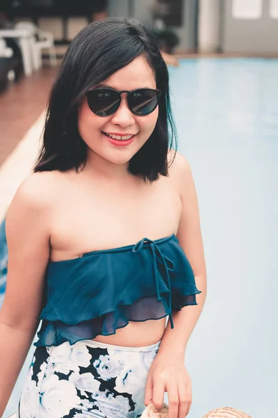 Portrait of beautiful woman relaxing in swimming pool, Recreation sport outdoor and summer vacation., Pretty woman in swimsuit with her hat relaxing sunbathing beside poolside. Summer holiday concept.