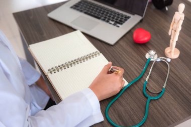 İncelenmesi ve hastanın sağlık raporu onun office., profesyonel sağlık stetoskop enstrüman sağlık işaretleyiniz ve Doktor çalışma alanında kişisel dizüstü bilgisayar için yazma kadın tıp doktoru.