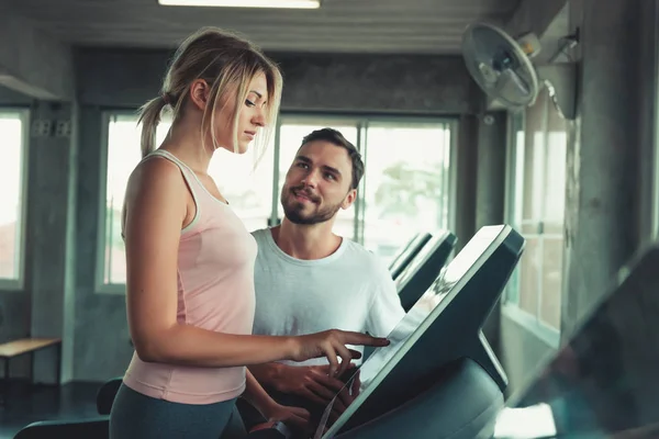 Trainer instructing to runner to exercising on treadmill machine for the right performance., Portrait of personal trainer man and female runner in fitness gym., Healthy and sport concept.
