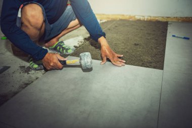 İnşaat işçisinin kapatılması, şantiyede hizalama için kauçuk çekiç kullanırken fayans kaldırım kuruyor., Meslek ve sanayi konsepti.