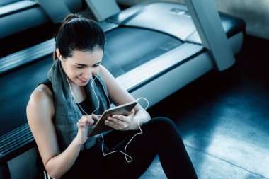 Sportif kadın fitness club., spor, spor ve boş zaman faaliyetleri kavramı egzersiz sırasında kulaklık ile müzik dinlemek Asyalı kadın portresi treadmill egzersiz sonra smartphone kullanıyor.