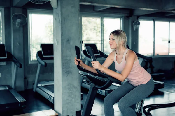 Porträtt av attraktiv kvinna är träning cykling övning i Fitn — Stockfoto