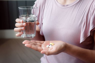Yakın çekim kadın el Holding cam, su iken alarak hap olduğunu