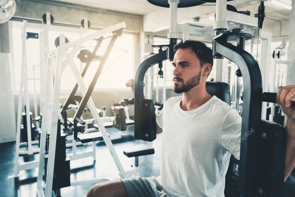Handsome Man is Exercising With Pectoral Machine in Fitness Club