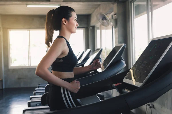 Retrato de la mujer bonita es entrenamiento en la máquina de cinta de correr en el gimnasio — Foto de Stock