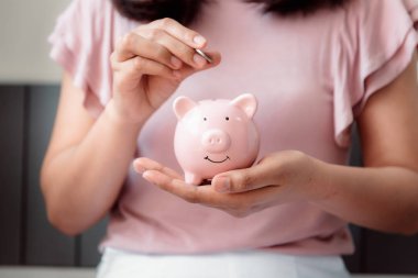 Yakın çekim Kadın el Piggy banka içine para sikke koyarak 
