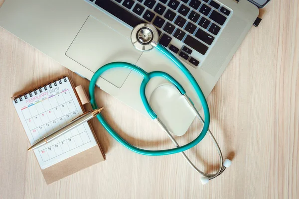 Business Healthcare Medicine and Insurance Concept.Top View of Stethoscope on a Laptop With Calendar Checkup Concept., Annual Doctor Appointment for Physical Check-Up Against Wooden Background