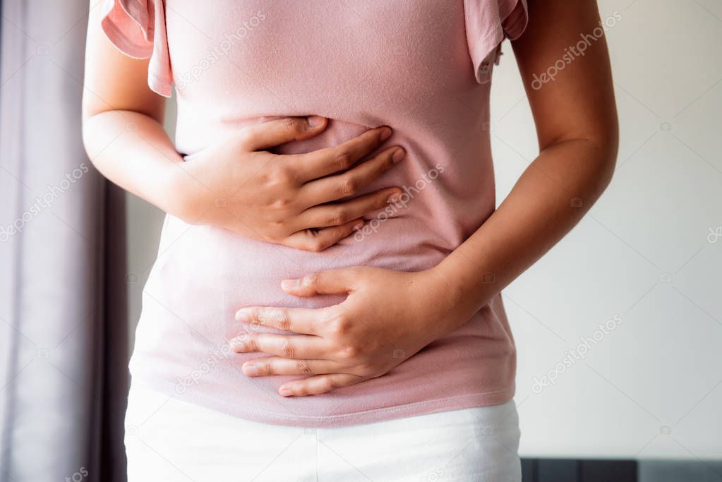 Woman is Having Stomach Ache or Menstrual Period, Close-Up Portrait of Young Woman is Suffering From Abdominal Pain at Her Home. Healthcare and Medicine Concept.