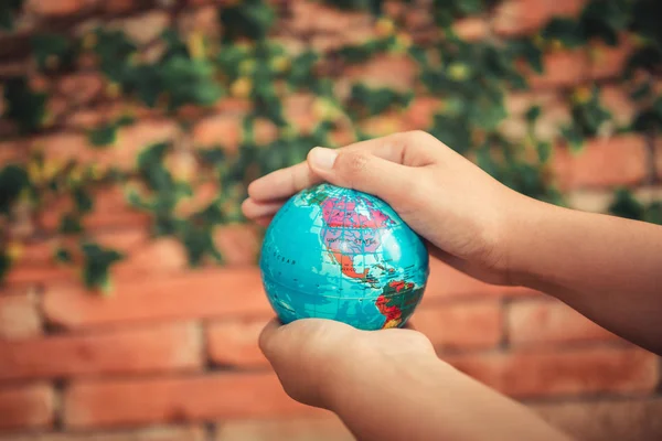 Save The Earth and Care Environment Concept, Close-up Portrait of Woman is Holding Mockup Global in Her Hands on Tree Leave Background. Save The Planet and Traveling Conceptual.