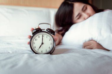 Ses veya çalar saat kavramı Snoozing kapatma, güzel kadın Waking Up in yatak odası iken Her el at sabah Zamanlayıcı çalar saat genişletiyor.