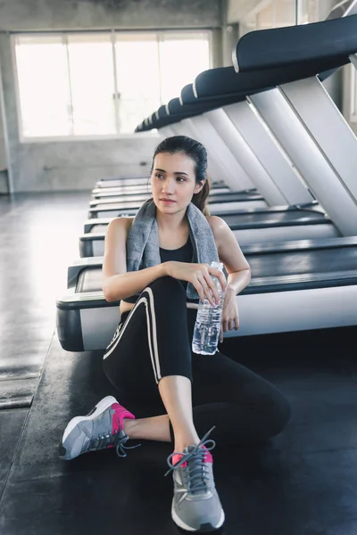 El retrato de la mujer asiática bonita se ejercita en el club de la aptitud, la mujer atractiva está descansando después de ejercitarse trotando en la máquina de la cinta de correr en el gimnasio, el club deportivo y el concepto sano . — Foto de Stock