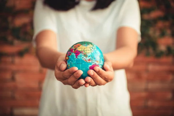 Save The Earth and Care Environment Concept, Close-up Portrait of Woman is Holding Mockup Global in Her Hands on Tree Leave Background. Save The Planet and Traveling Conceptual.