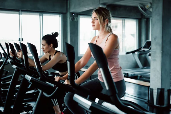 Kvinnor grupp gör Workout cykling övning i Fitness Club, porträtt av ganska attraktiv kaukasiska kvinna cykling utbildning i gym, vacker flicka i Sportswear med leende medan Workout. — Stockfoto