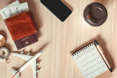 Navigasyon Journey Turizm planlama keşfedin., tatil gezisi için seyahat hedef planı., ahşap bir masa üzerinde düzen takvimi, uçuş bilet, pusula, uçak modeli ve cep telefonu üst görünümü.