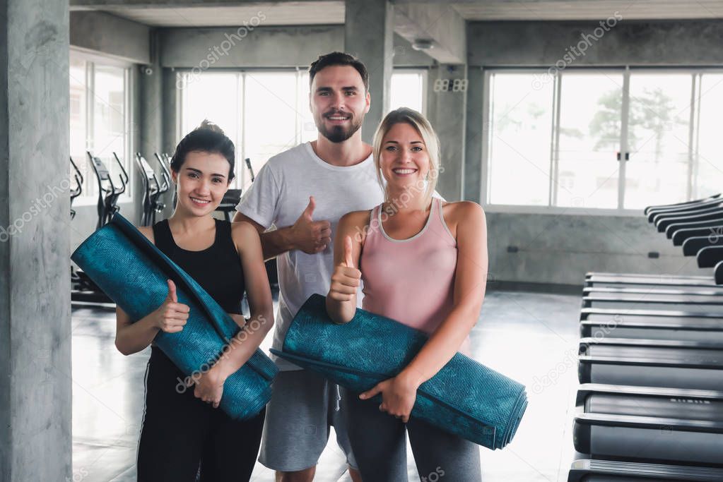 Portrait of Sporty Teenagers in Sportswear at Gym Club , Group of People are Preparing for Practice Yoga With Trainer in Fitness Class Room, Sport and Healthy Concept.