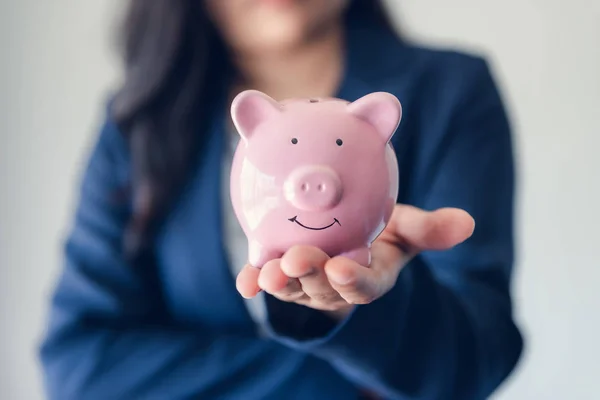 Business Woman Investor Holding Piggy Bank for Money Savings on Her Hands, empresaria asiática con traje uniforme que muestra el ahorro de dinero mientras mira la cámara, la inversión y el concepto financiero . — Foto de Stock