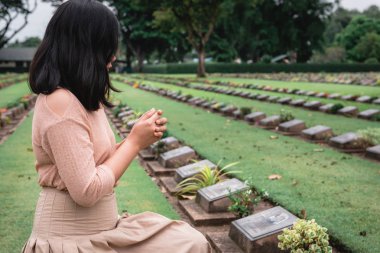 Close-Up of Religious Christian Woman Hands Clasped While Honoring and Praying to Military in War Cemetery. Teenager Woman in Expression Sadness and Pray for Soldier Prisoner of War in Tomb.