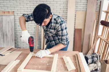 Marangoz, marangozluk atölyelerinde kereste işçiliği yapıyor. Atölyedeki ahşap mobilyalar için kereste kalaslarına vida kullanıyor. DIY İşçilik, İş Marangozları Konsepti