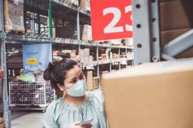Covid-19 Salgını sırasında rafta Malları Seçerken ve Bakarken Süpermarket Dükkanında Alışveriş Arabalı Yüzü Maskeli Müşteri Asyalı Kadın. Coronavirus Kapsamlı Durum 