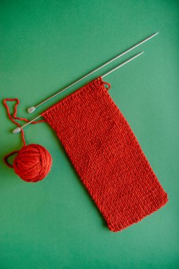 Parlak kırmızı fular örgü iğne ile. Yeşil arka plan üzerinde. Yeşil ve kırmızı kontrast.