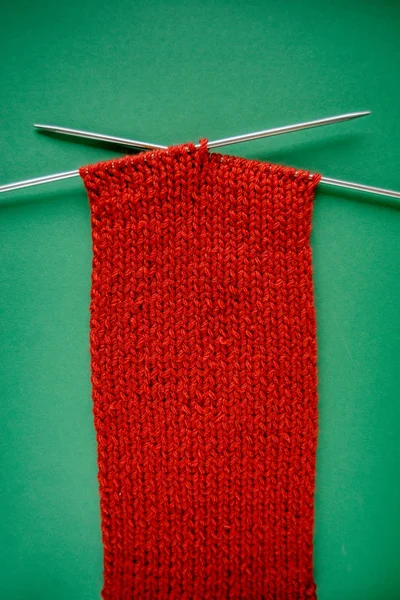 Écharpe Rouge Vif Avec Aiguilles Tricoter Sur Fond Vert Contraste — Photo