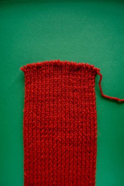 亮红色围巾 带针织针 绿色背景 绿色和红色对比度 — 图库照片