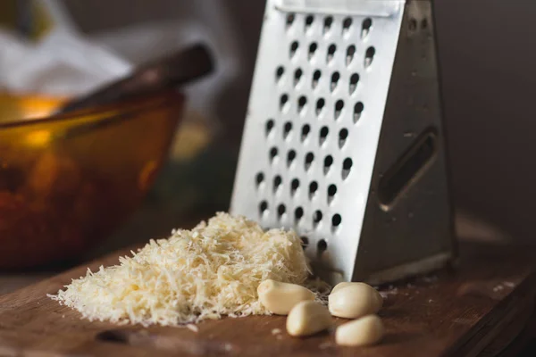 Biraz sarımsak ve ahşap breadboard üzerinde peynir. Demir rende. Yuvarlak Masa.
