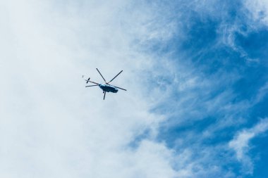 Parlak mavi gökyüzü ile bazı bulutlar büyük helikopterde. Beş kanatları ve uzun.