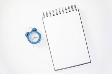 Beyaz eskiz defteri turuncu kalem ve mavi çalar saat ile. Eğitim ve planlama kavramı, beyaz arka plan. Mock-up kavramı. Beyaz arka plan, izole, yakın çekim 