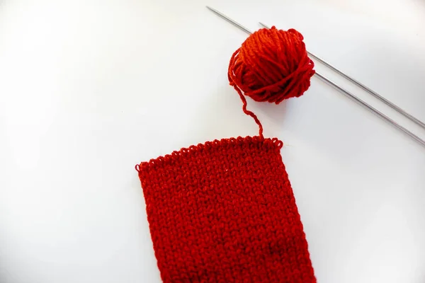 Red knitting scarf, not finished. Hobby and free time activities. Knitting threads.