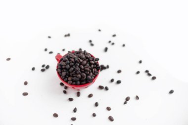 Kırmızı kahve fincanı kahve çekirdekleri ile boş. Kırmızı plaka üzerinde. Kahve molası