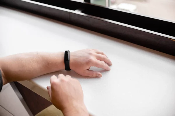 Man is wearing a fitness bracelet. Smart watch on the hand of a man. Pensioner Using Fitness Tracker. Horizontal top view everal objects