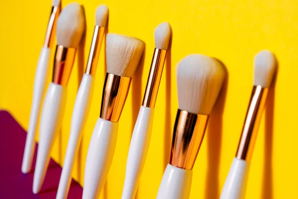 Makeup flat lay brushes yellow  and purple background. Horizontal top view copyspace. Beauty and make up