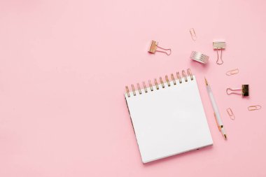 Kırtasiye işi, düz çizgi, yaratıcı kompozisyon. Zarfın üst yatay görünümü, sarmal tıkanma kağıt ataçları ve soyut pembe arkaplan üzerine bir kalem