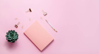 Kırtasiye işi, düz çizgi, yaratıcı kompozisyon. Zarfın üst yatay görünümü, sarmal tıkanma kağıt ataçları ve soyut pembe arkaplan üzerine bir kalem.